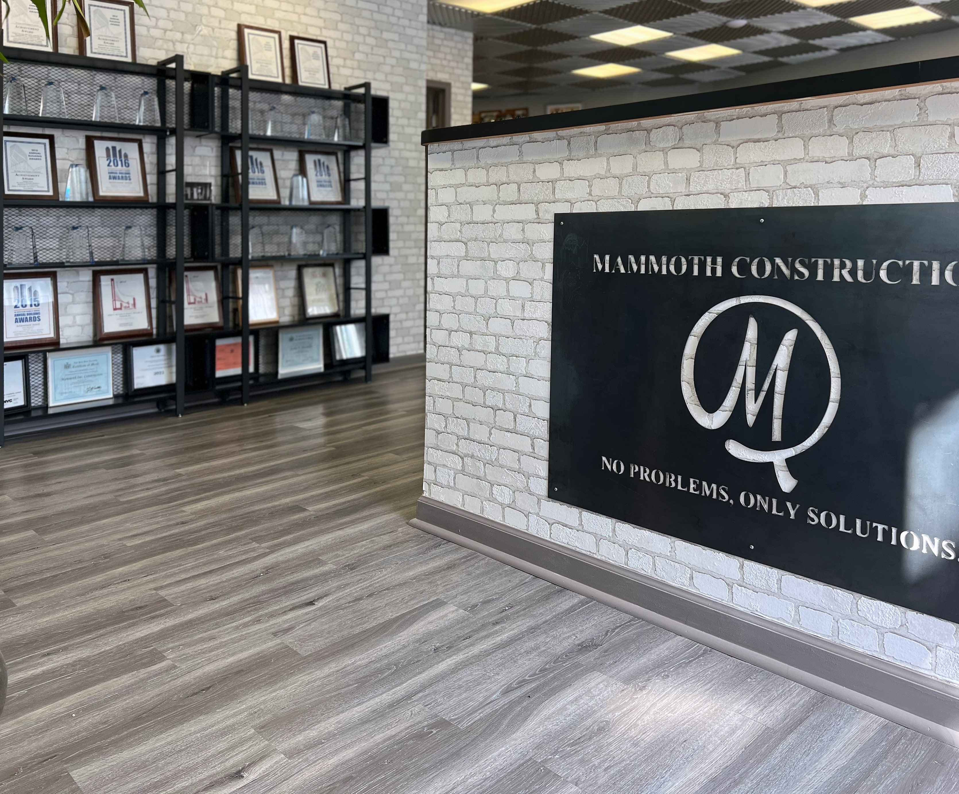 Office lobby with Mammoth Construction sign and award shelves on brick
